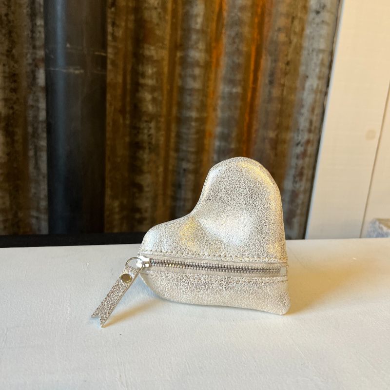Porte-monnaie cœur en cuir avec fermeture zippée, décliné en cuir blanc et paillettes dorées, présenté sur tôle d'atelier